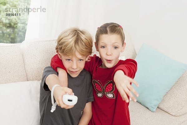 Ein Junge und ein Mädchen  die eine Spielkonsole benutzen.