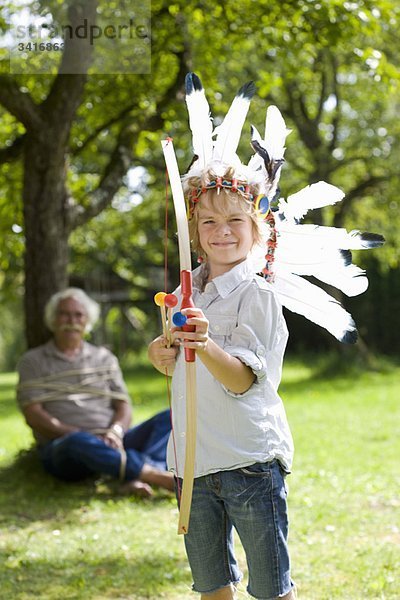 Verkleideter Junge mit Spielzeugbogen und Pfeilen