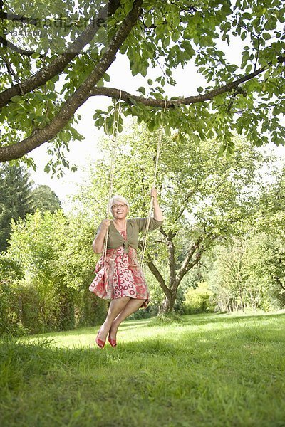 Großmutter beim Schaukeln im Garten