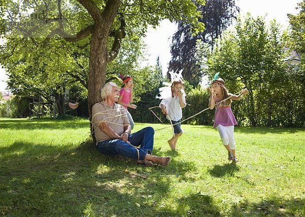 Enkelkinder binden Großvater an Baum