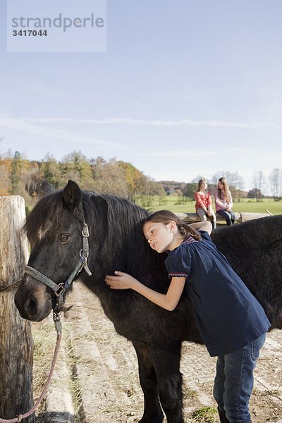 Mädchen streichelt ein Pony
