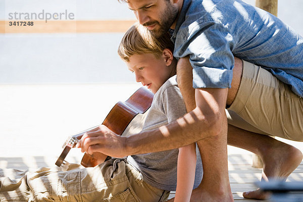 Vater und Sohn spielen Gitarre