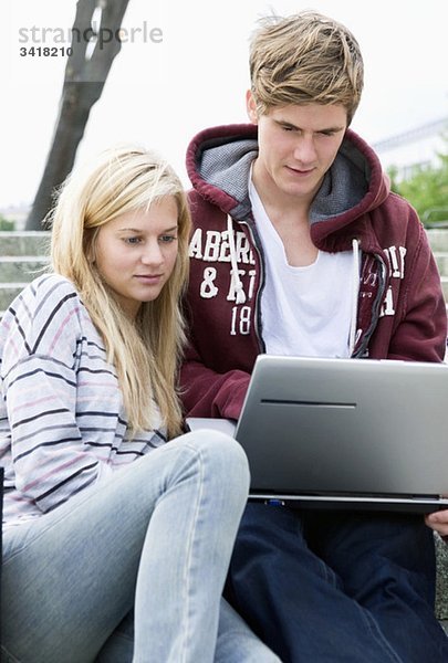 Zwei Studenten auf einer Steintreppe mit Laptop