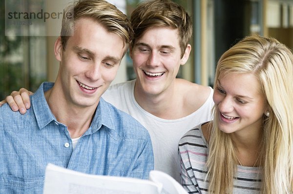 Drei glückliche Schüler beim Lesen der Broschüre
