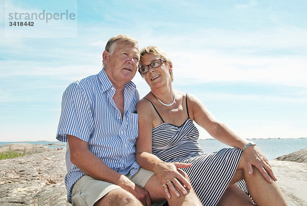 Zwei ältere Menschen am Strand sitzend