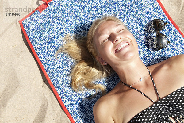 Frau am Strand liegend beim Sonnenbaden