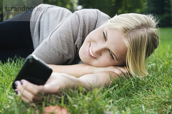 Glückliches Mädchen auf dem Rasen mit Telefon