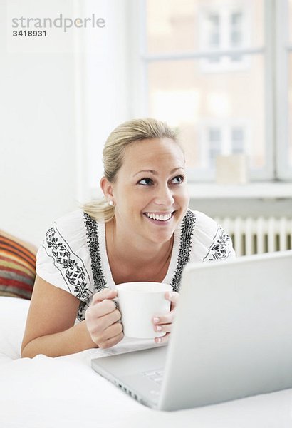 Glückliche Frau mit Computer und Kaffee