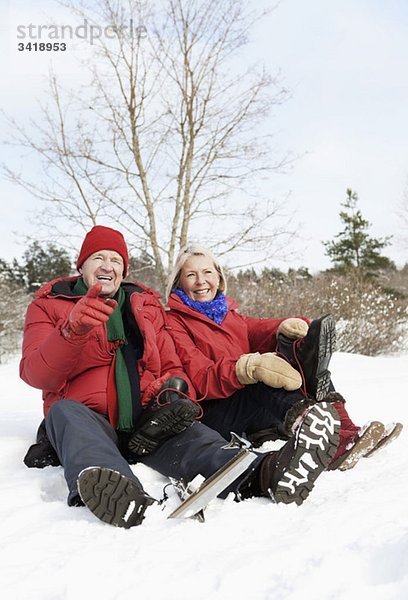 Zwei Senioren sitzen im Freien im Schnee.