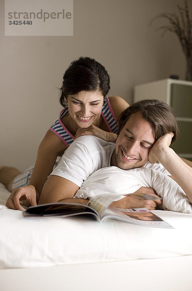 Mann und Frau lesen eine Zeitschrift im Bett  Flachwinkelansicht