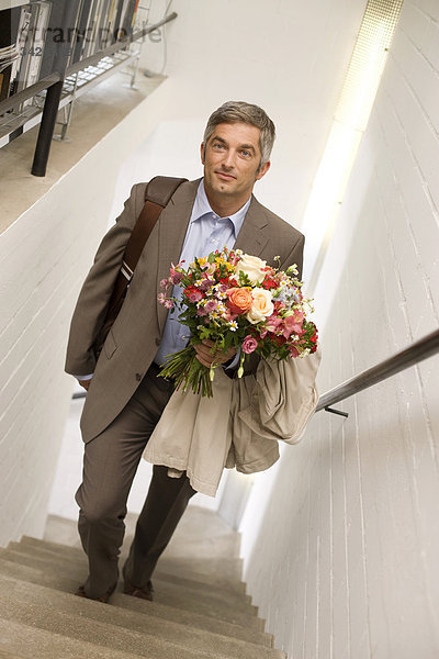 Mann mit Blumenstrauß geht die Treppe hinauf  Erhöhte Ansicht