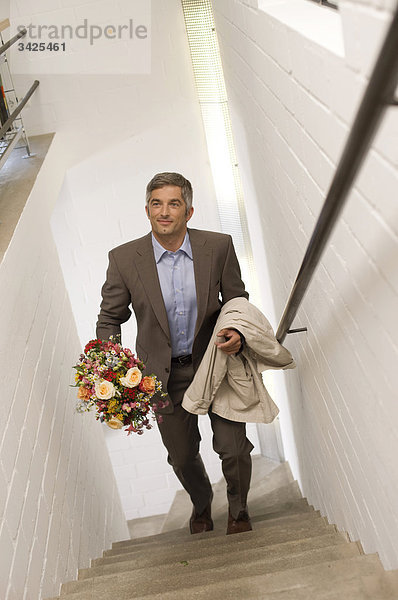 Mann mit Blumenstrauß geht die Treppe hinauf  Erhöhte Ansicht