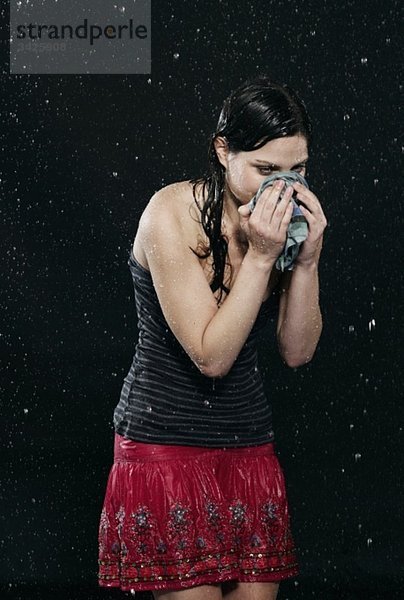 Frau im Regen stehend  niesend.