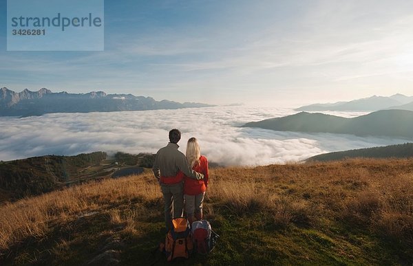 Österreich  Steiermark  Reiteralm  Wandererpaar mit Blick über die Wolken  Rückansicht