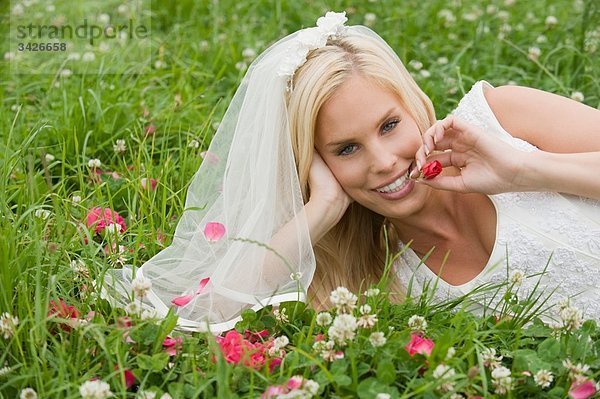 Braut auf der Wiese liegend  lächelnd  Portrait.