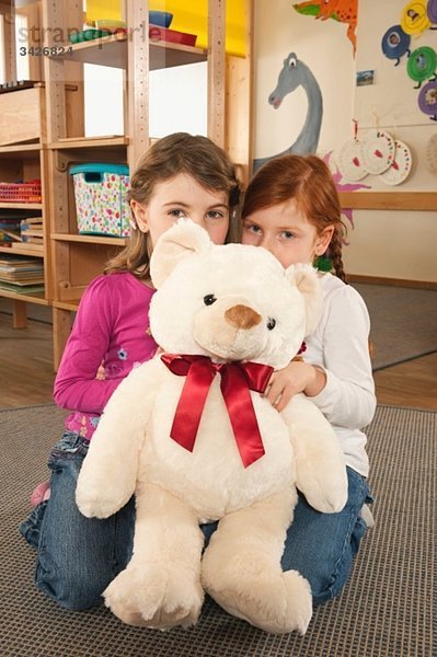 Deutschland Zwei Mädchen (4-5)  (6-7) im Kinderzimmer mit Teddy  Portrait