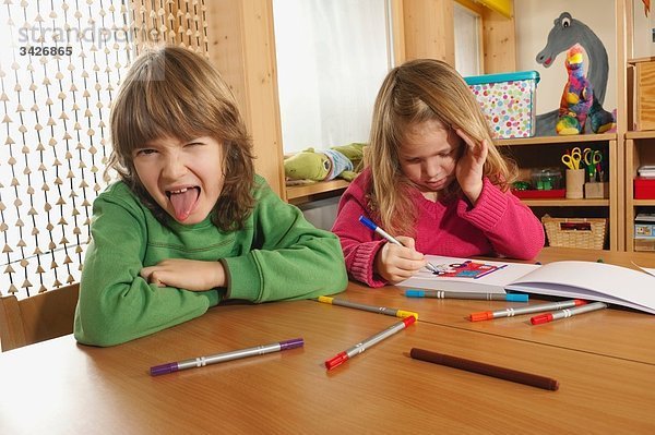 Deutschland  Junge (6-7) und Mädchen (4-5) im Kinderzimmer  Zunge herausstreckend  Portrait
