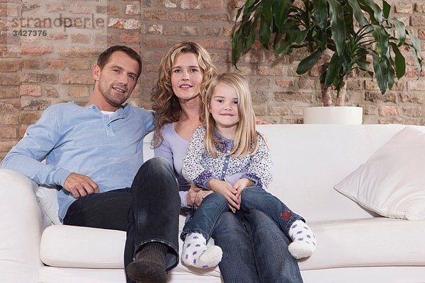 Deutschland  Köln  Familie auf Sofa im Wohnzimmer sitzend  lächelnd  Portrait