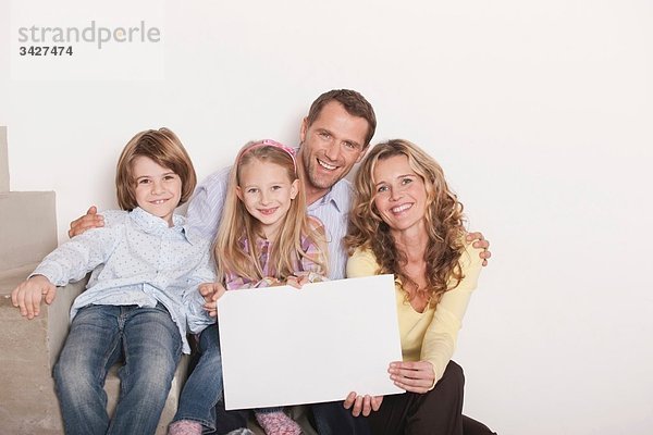 Deutschland  Köln  Familie sitzend auf Treppenstufen mit Laptop  lächelnd  Portrait