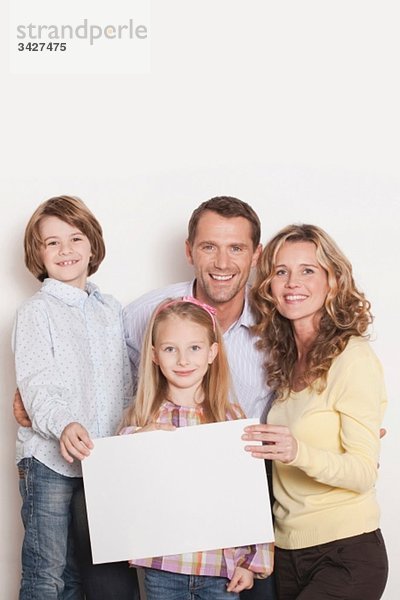 Deutschland  Köln  Familie mit unbedrucktem Karton  lächelnd  Portrait