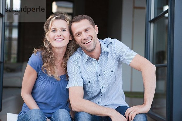 Deutschland  Köln  Paar auf der Terrasse sitzend  lächelnd  Portrait