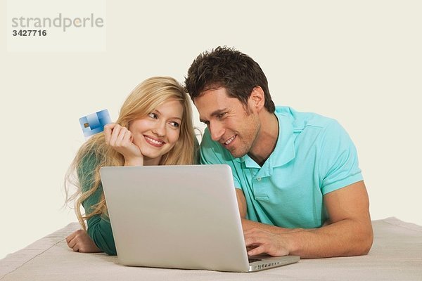 Paar liegend und mit Laptop  lächelnd