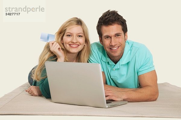 Paar liegend und mit Laptop  lächelnd  Portrait
