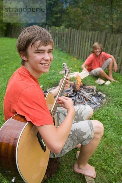 Österreich  Salzburger Land  Jugendliche (14-15) im Garten  am Lagerfeuer sitzend