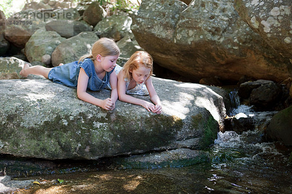 Mädchen liegen auf Felsen am Fluss
