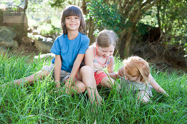 Kinder sitzen auf Rasen