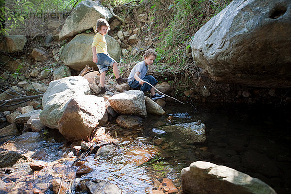 Jungen auf Felsen am Fluss