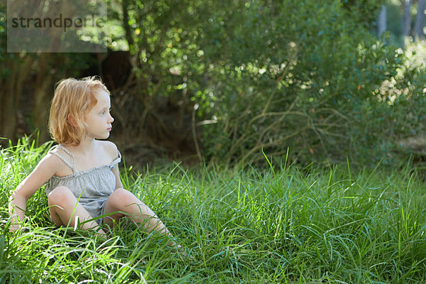 Kleines Mädchen im Gras sitzend