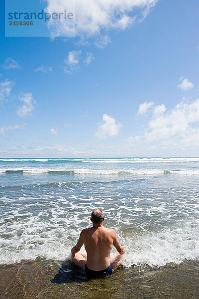 Auckland  Mann beim Meditieren am Muriwai-Strand