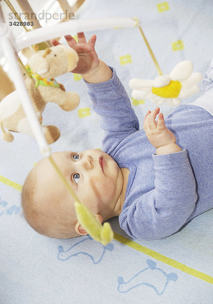 Baby im Kinderbett greift nach hängendem Spielzeug  Erhöhte Ansicht