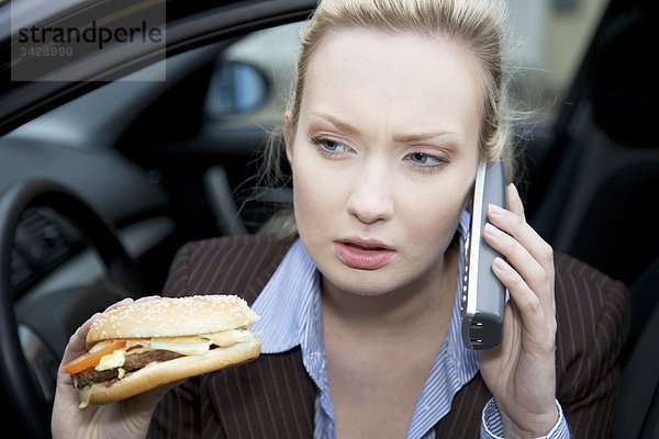 Geschäftsfrau hält einen Hamburger und telefoniert  Close-up