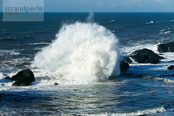 Wellen über Steinblöcken im Ozean