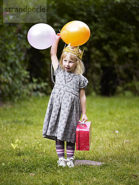 Skandinavien  Schweden  Stockholm  Mädchen tragen Krone stehenden im Park hält Ballons und Tasche