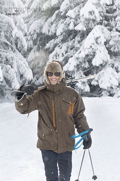 Junger Mann mit Skiern auf den Schultern