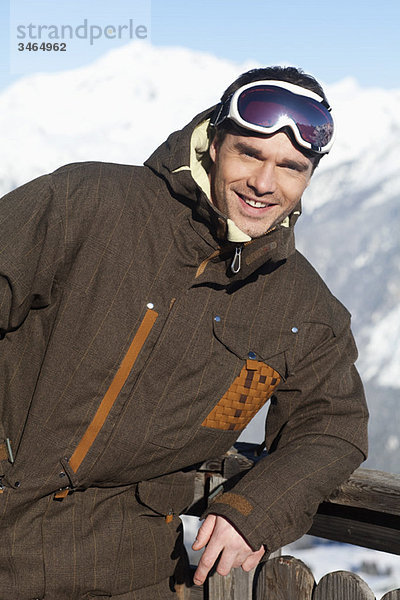 Junger Mann in Skikleidung lächelnd vor der Kamera