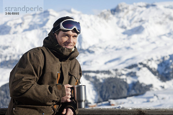 Junger Mann in Skibekleidung hält Glas