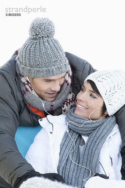 Junges Paar in Winterkleidung  gemeinsam Musik hören