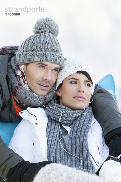 Junges Paar in Winterkleidung  gemeinsam Musik hören