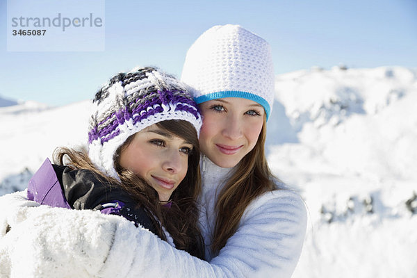 Zwei Teenagermädchen in Winterkleidung  umarmend
