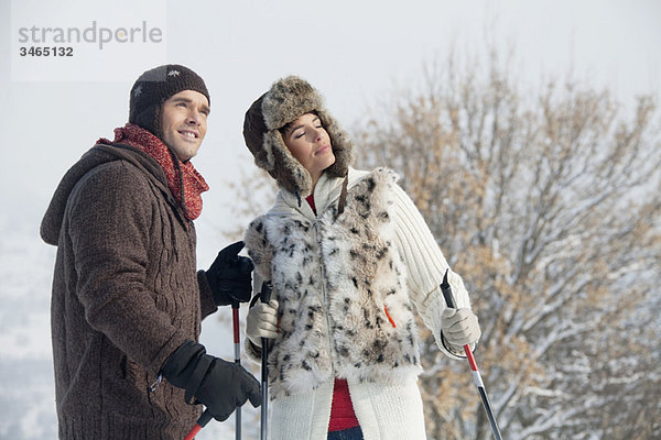 Junges Paar in Winterkleidung mit Skistöcken
