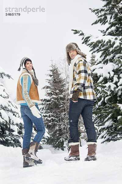 Junges Paar  das im Schnee läuft  zurückblickend