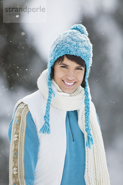 Junge Frau in Winterkleidung lächelnd vor der Kamera