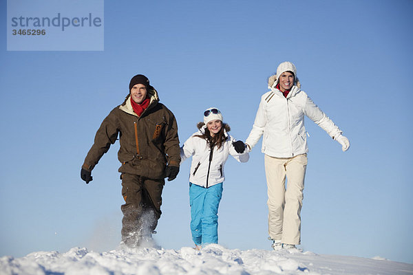 Paar und Tochter in Skibekleidung beim Wandern im Schnee