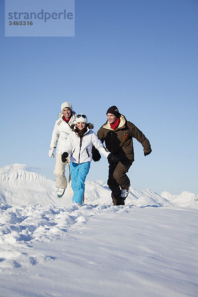 Paar und Tochter in Skibekleidung laufen im Schnee