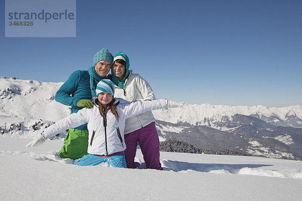 Paar und Tochter in Skibekleidung  spielen im Schnee