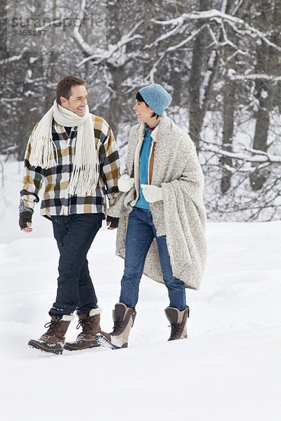 Junges Paar schaut sich an  geht im Schnee spazieren
